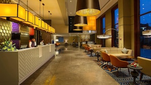 A hotel lobby with a reception desk, seating area, and large windows. - Grand Mercure Mysore (Mysore)
