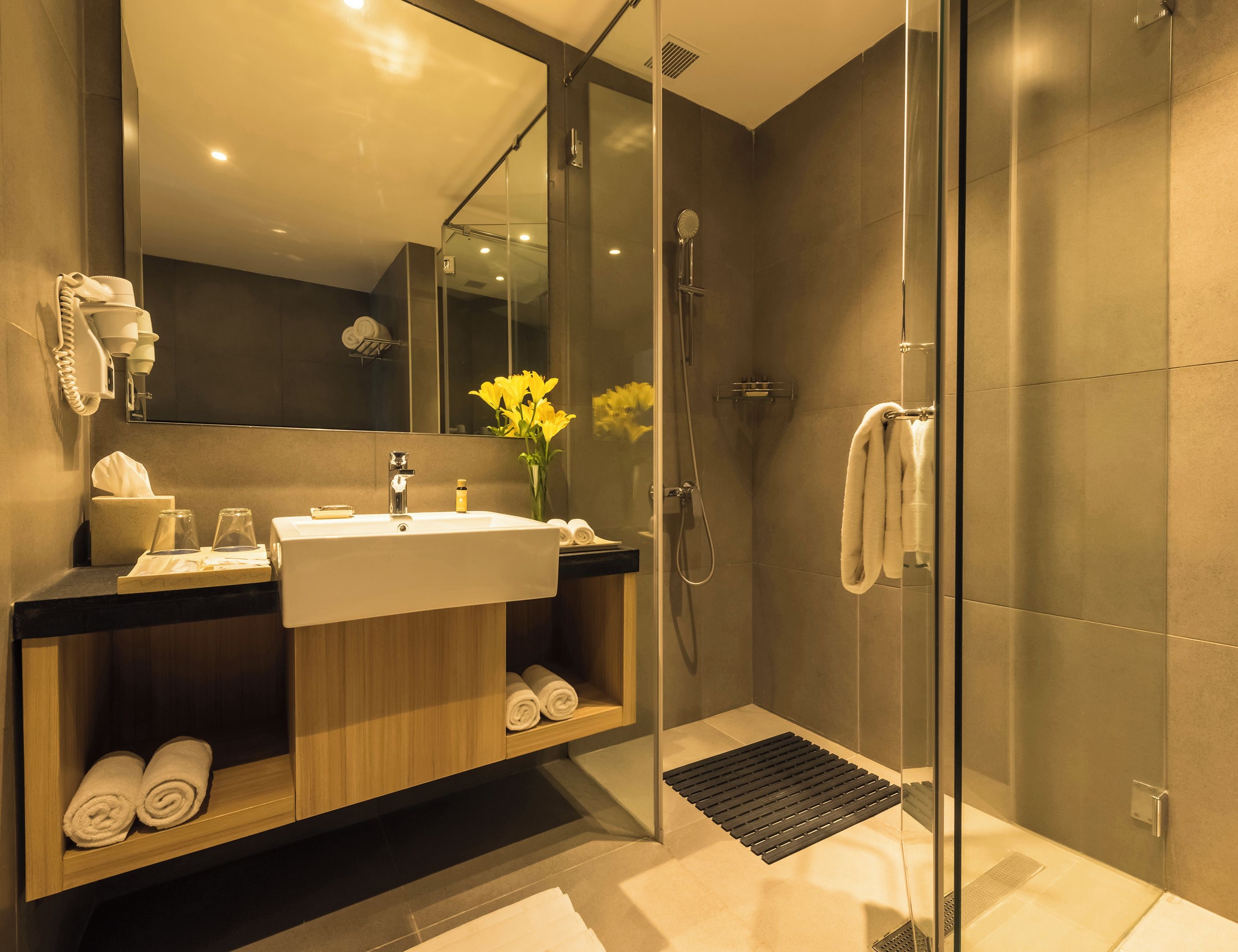 A modern bathroom with a glass-enclosed shower, a sink with a mirror above it, and a towel rack with towels.