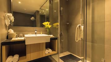 A modern bathroom with a glass-enclosed shower, a sink with a mirror above it, and a towel rack with towels.