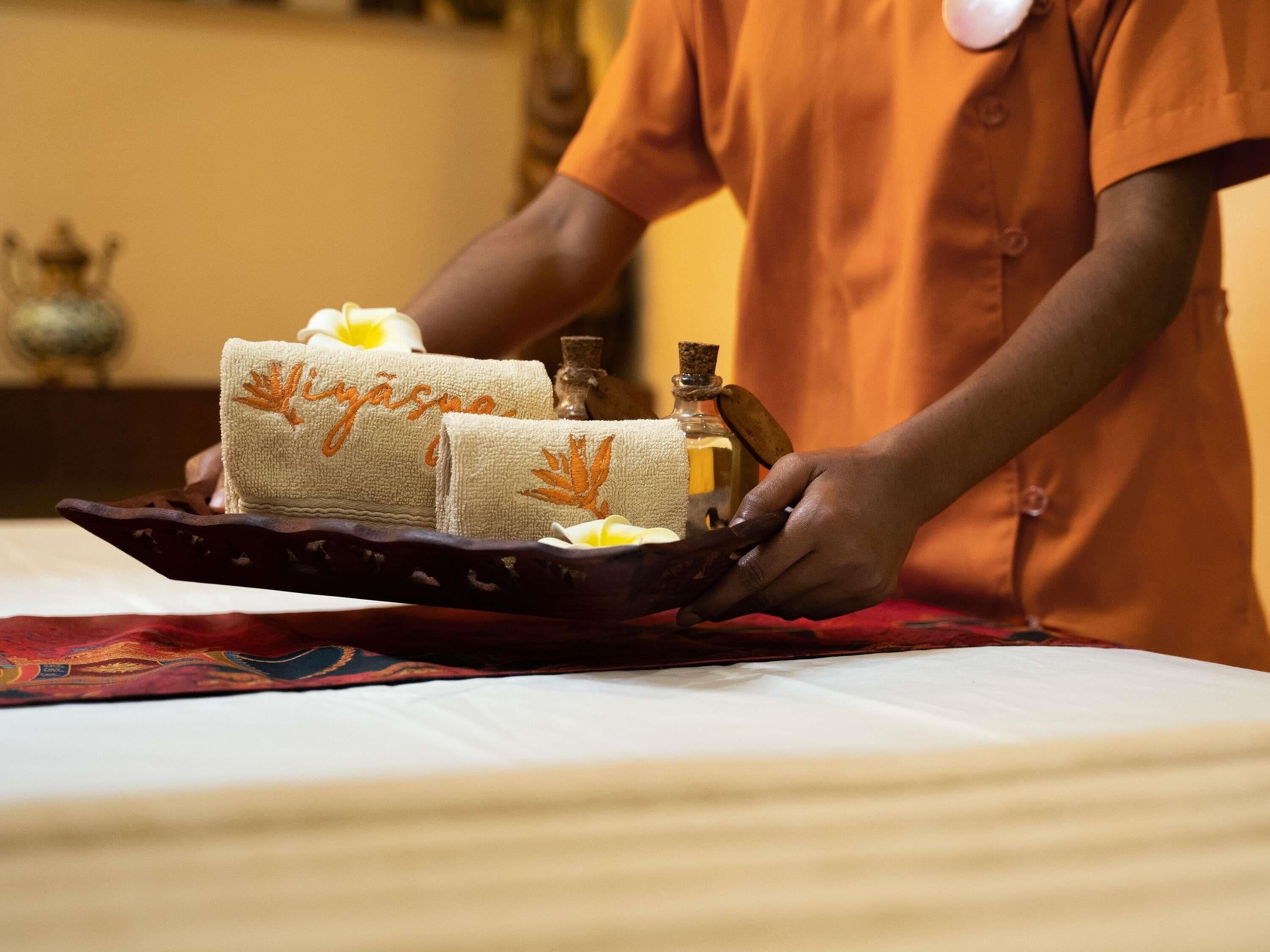 A person holding a tray with towels and a bottle.