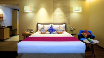 Une chambre d’hôtel avec un grand lit, des tables de chevet, un bureau avec un téléphone, une chaise et une petite table sur laquelle est posé un vase.