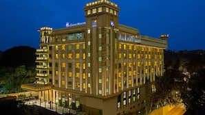 A multi-story hotel with a prominent Grand Mercure sign, multiple balconies, and a well-lit facade. - Grand Mercure Mysore (Mysore)
