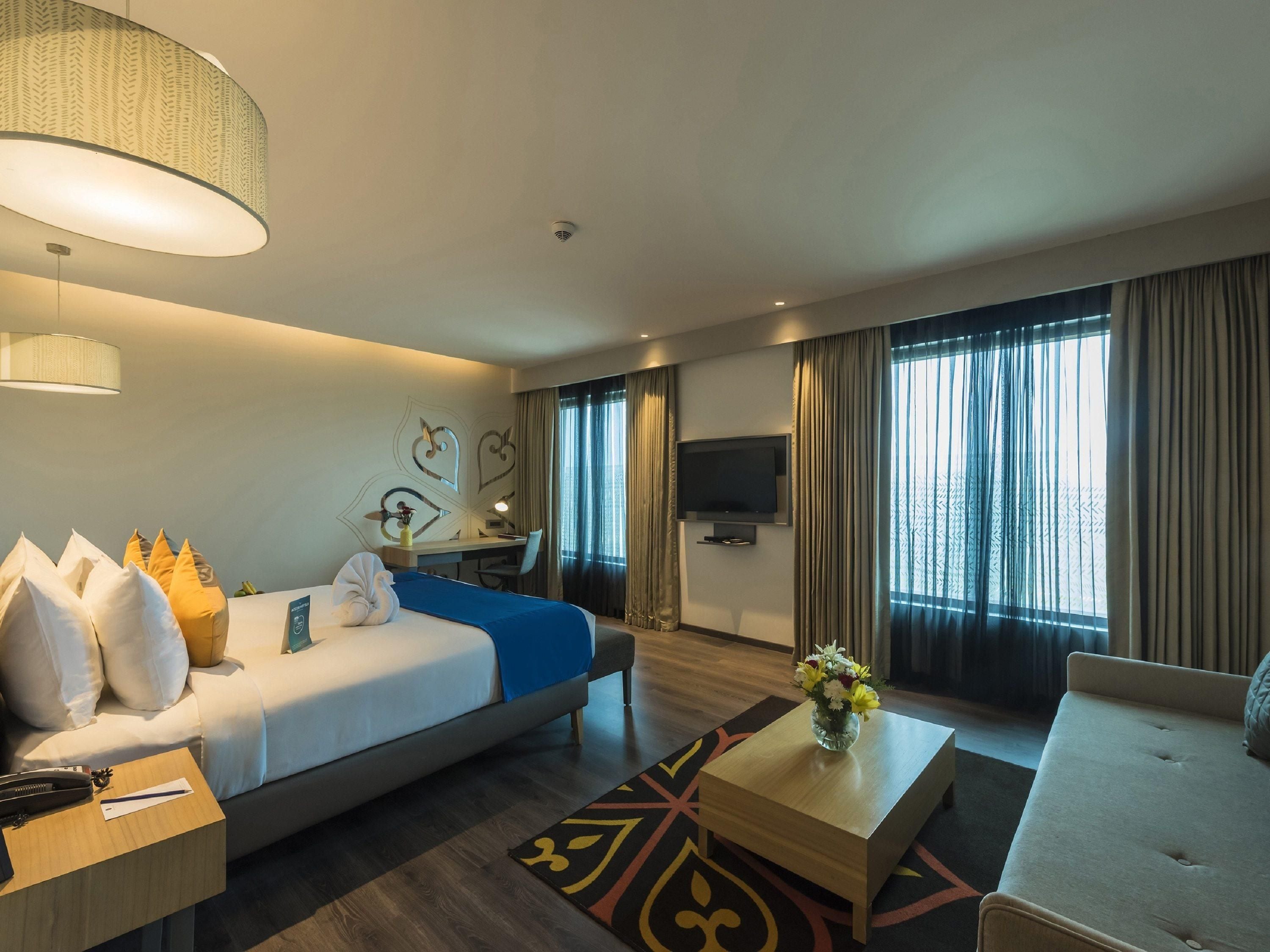 A hotel room with a bed, a desk, a TV, and a sofa.