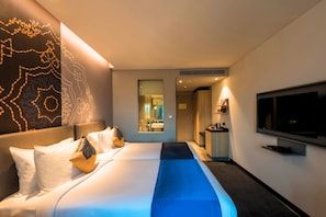 A hotel room with a large bed, a television, and a view of the bathroom. - Grand Mercure Mysore (Mysore)
