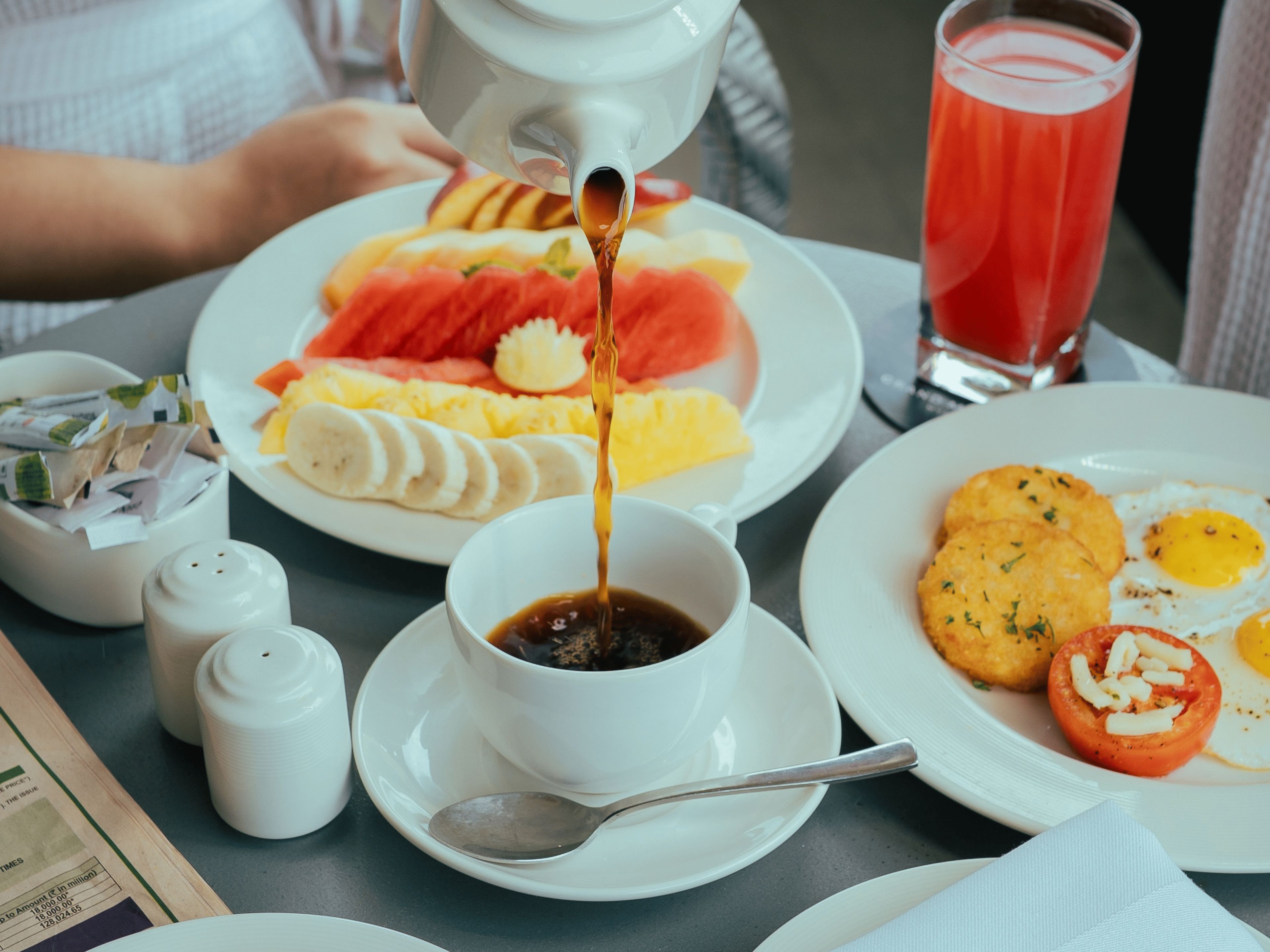 Un desayuno con diversos alimentos, como huevos, tomates y una bebida.