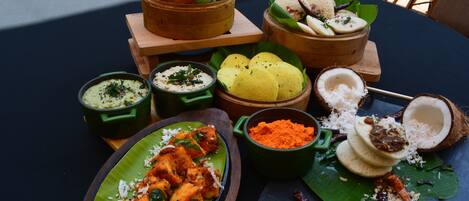 A table with various dishes, including fried items, rice, and a coconut shell with coconut shavings.
