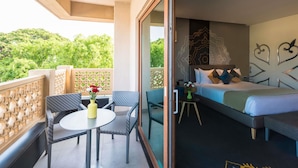 A balcony with a table and chairs, a bed with pillows, and a decorative wall. - Grand Mercure Mysore (Mysore)
