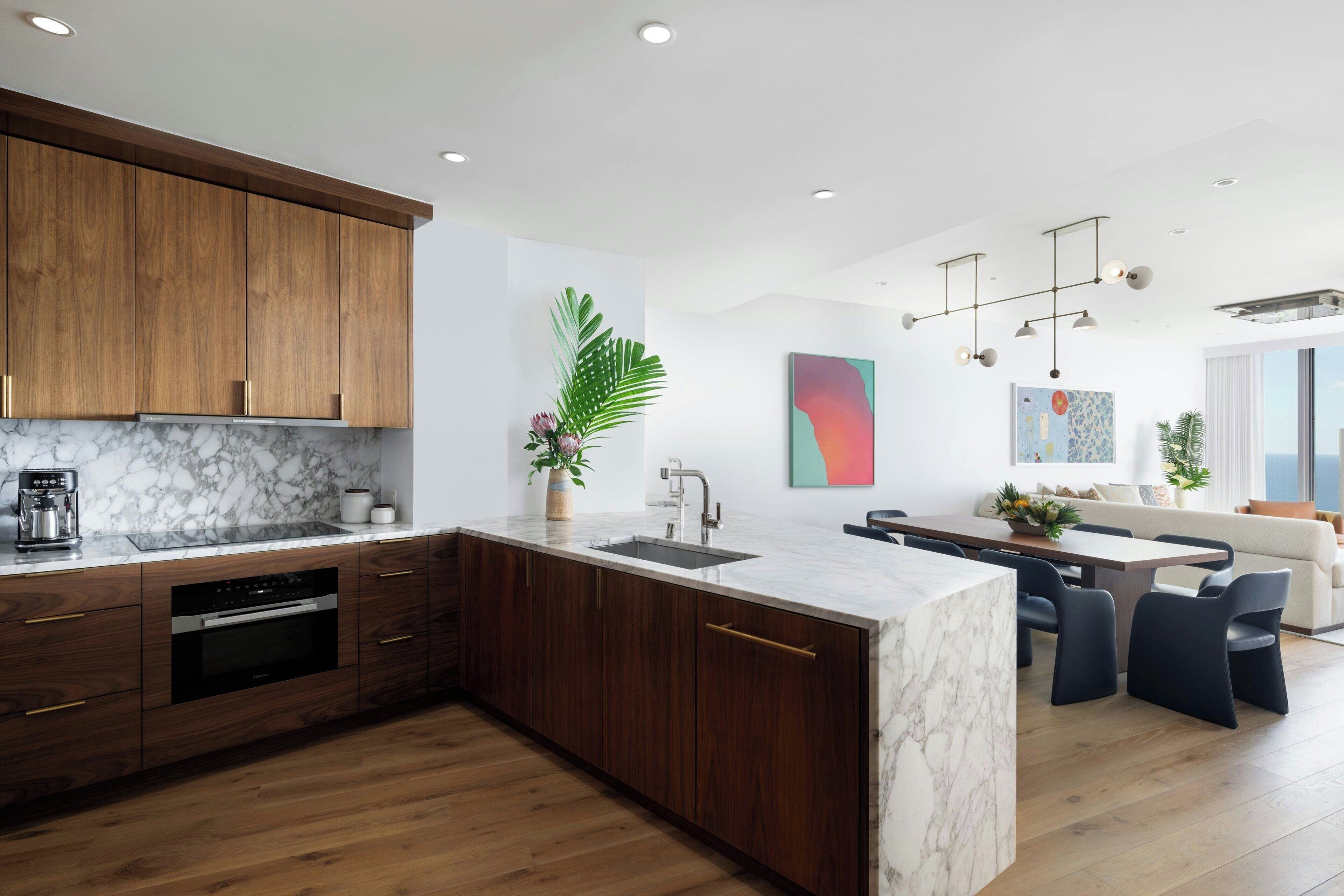 A modern kitchen with wooden cabinets, a marble countertop, and a built-in oven.