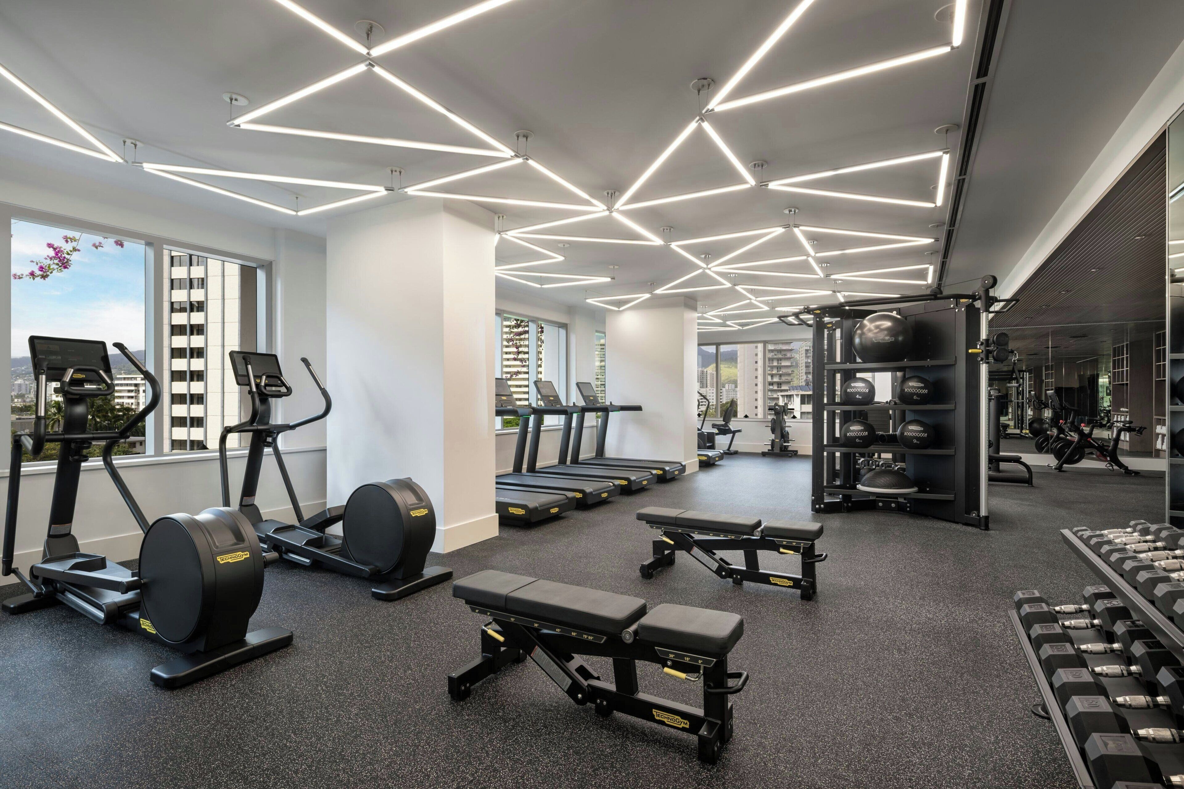 A modern gym with treadmills, elliptical machines, and free weights.