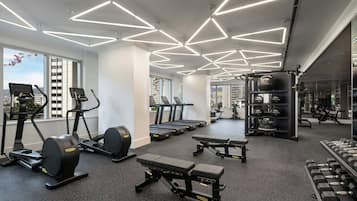 A modern gym with treadmills, elliptical machines, and free weights.