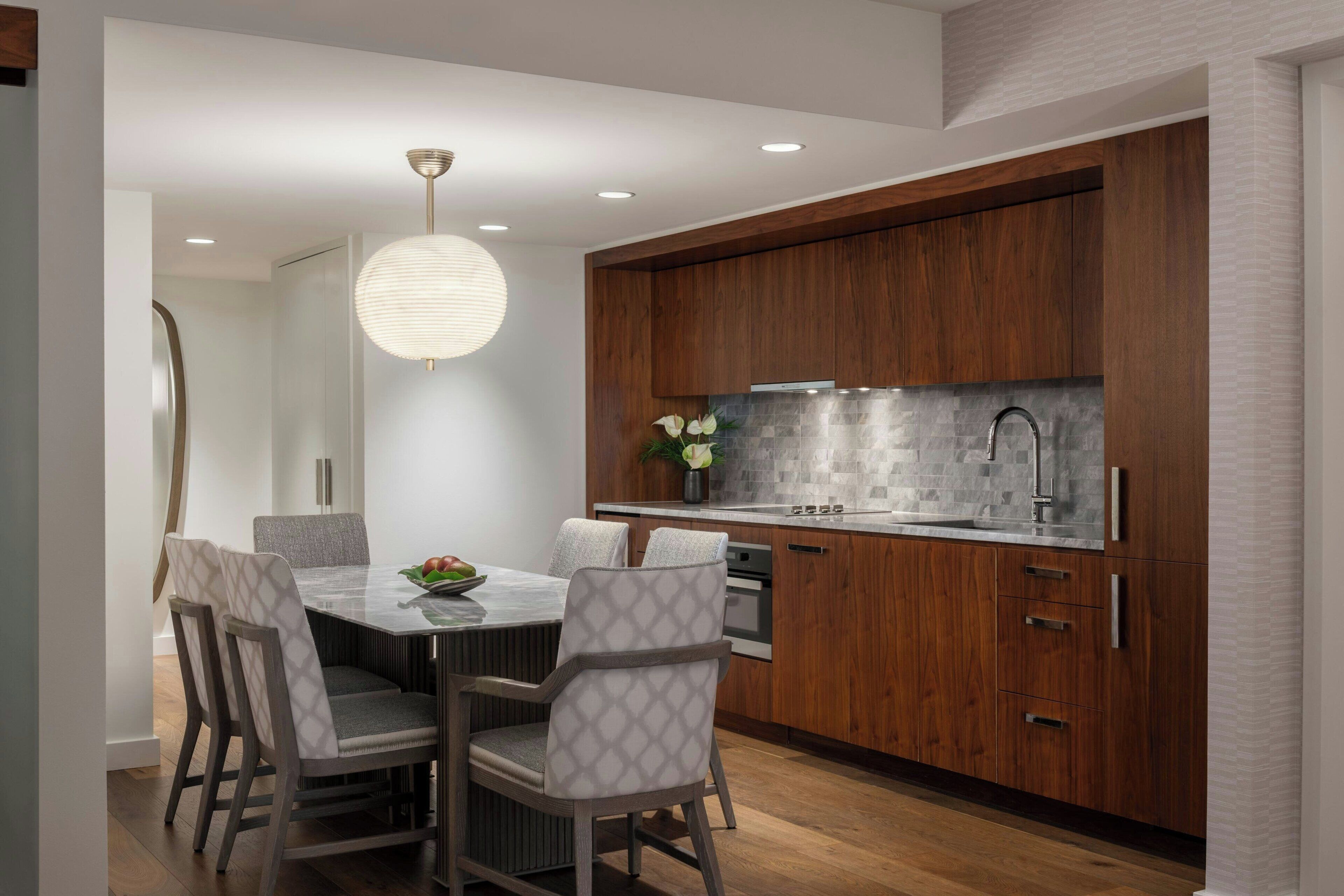 A modern kitchen with wooden cabinets, a stainless steel sink, and a dining area with a round table and chairs.