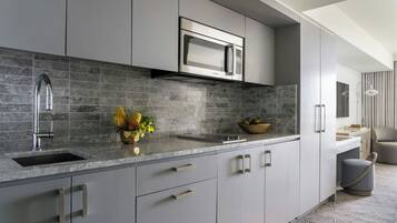 Une cuisine moderne avec des meubles gris, un four à micro-ondes en acier inoxydable et un plan de travail en marbre.