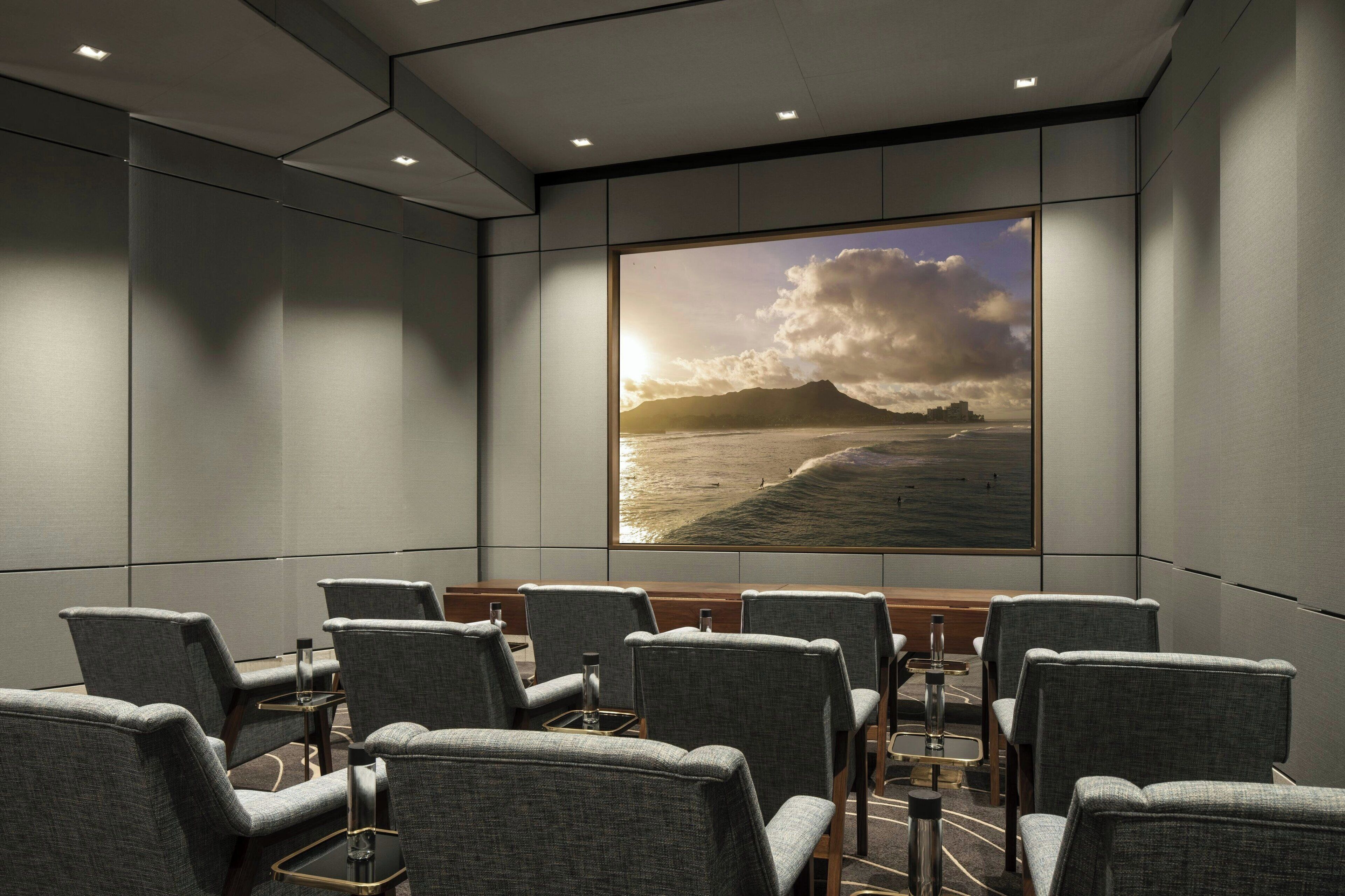 A conference room with a large window overlooking a beach at sunset.