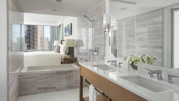Une salle de bain moderne avec un grand miroir, deux lavabos, une baignoire et une douche.