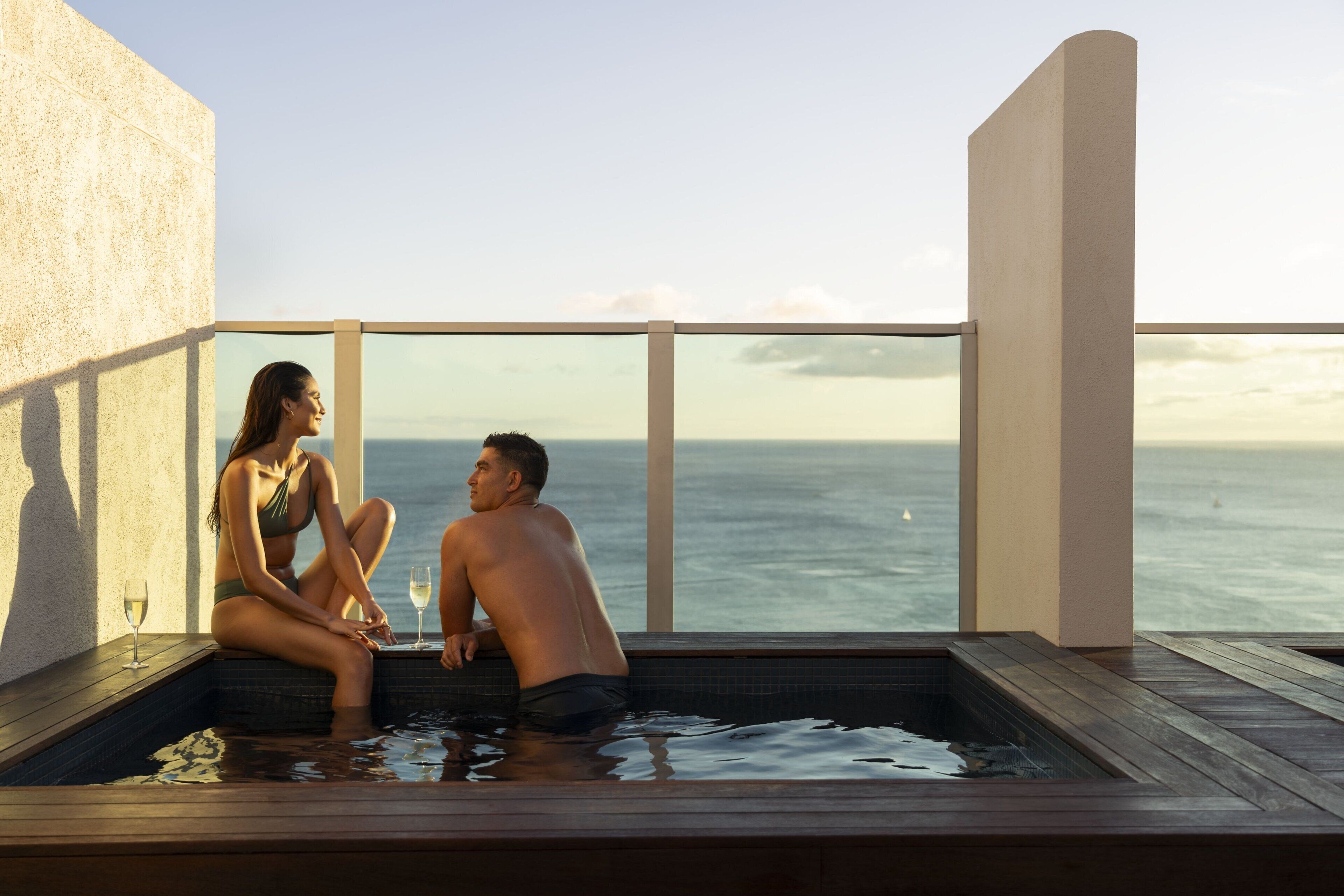 Un couple est assis dans un jacuzzi, avec vue sur l’océan.