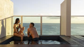 Un couple est assis dans un jacuzzi, avec vue sur l’océan.