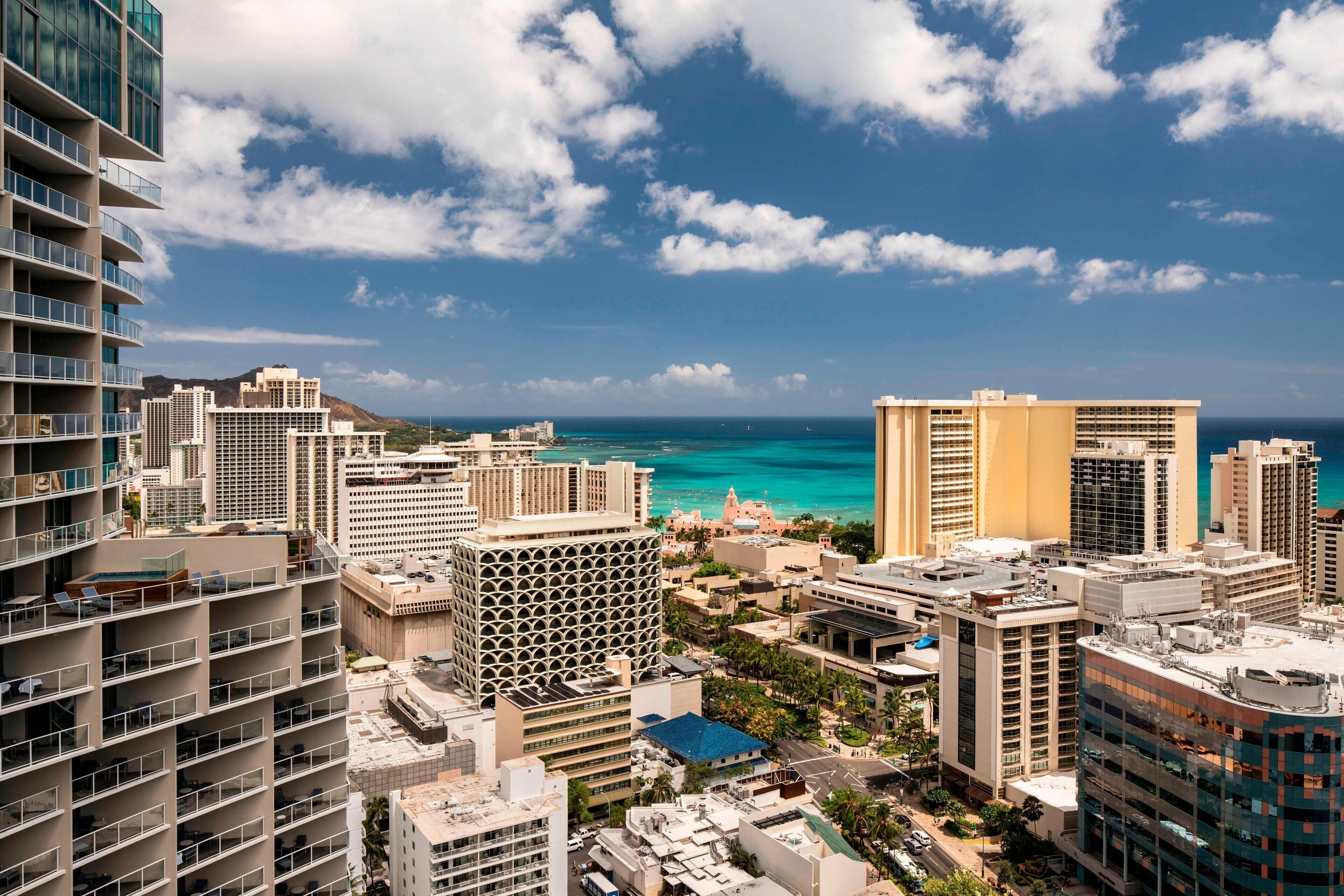 A high-rise hotel with multiple floors, a central courtyard, and a view of the ocean.