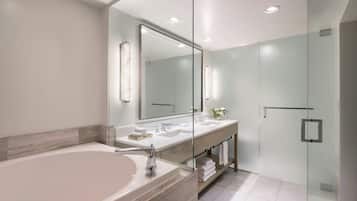 Ein modernes Badezimmer mit einer großen Badewanne, zwei Waschbecken, einer Duschkabine aus Glas und einem großen Spiegel.