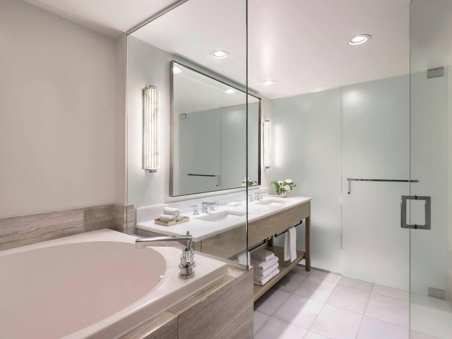 Ein modernes Badezimmer mit einer großen Badewanne, zwei Waschbecken, einer Duschkabine aus Glas und einem großen Spiegel.