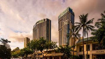 A city street with tall buildings, palm trees, and a PRADA store.