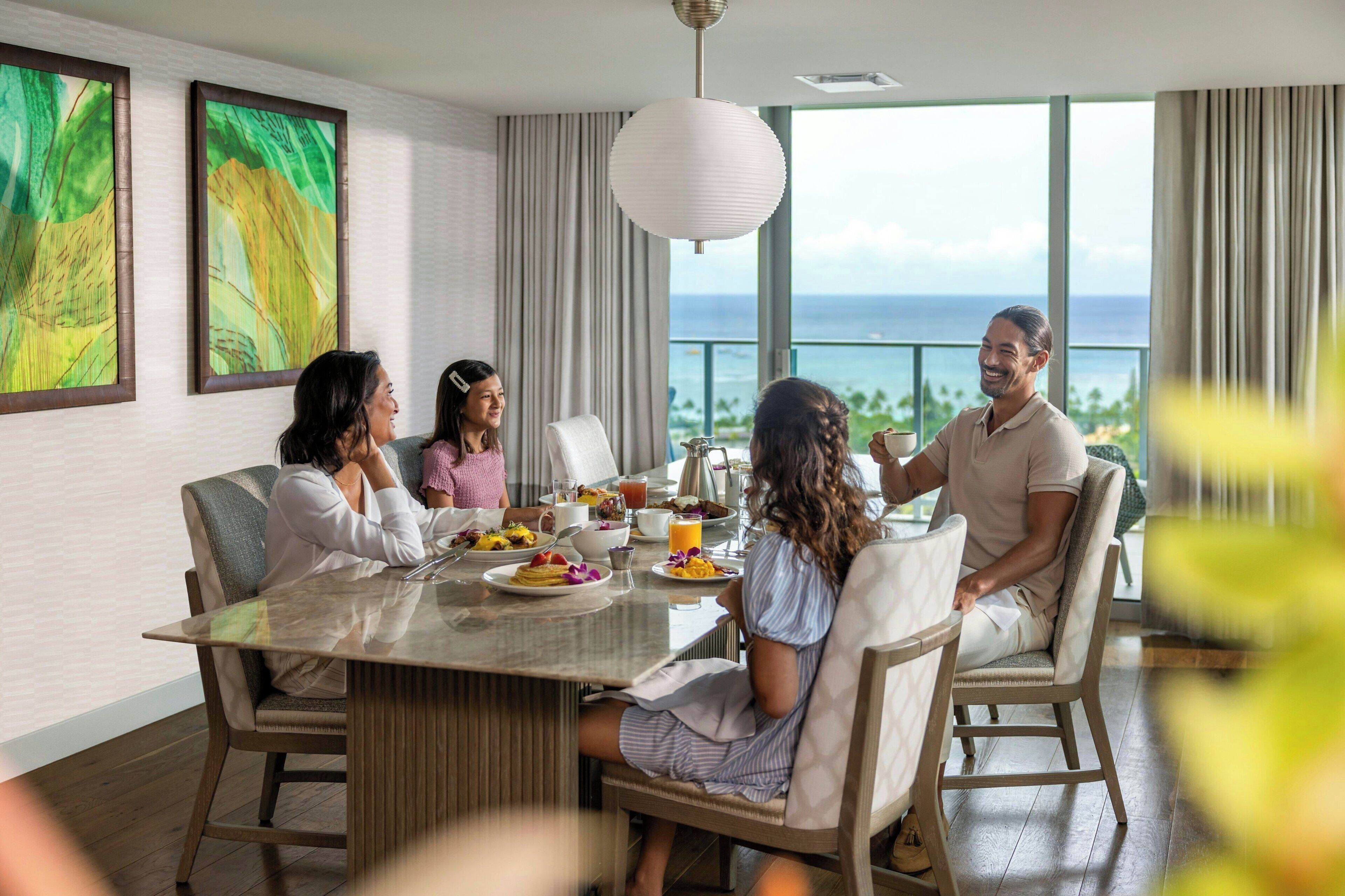 A dining area with a large table, chairs, and a view of the ocean.