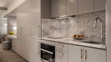 Una cocina moderna con armarios grises, salpicadero de mármol, electrodomésticos de acero inoxidable y un frutero sobre la encimera.