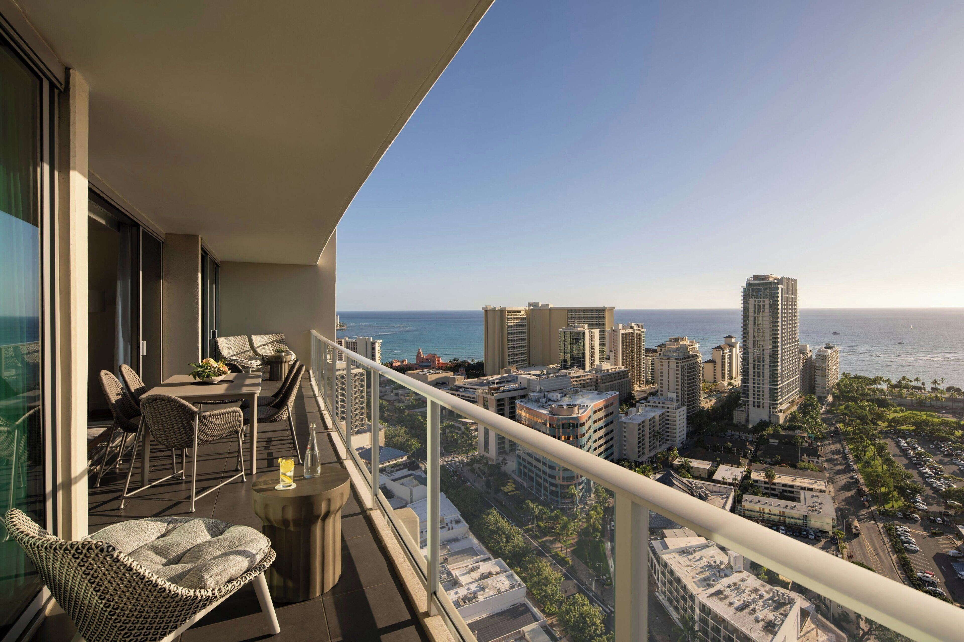 A balcony with a city view, outdoor furniture, and a railing.