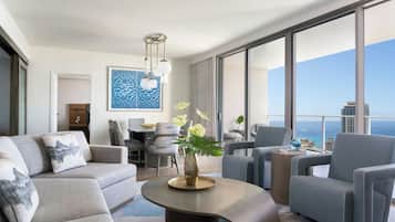 A modern hotel room with a large balcony, a dining area, and a view of the city skyline.