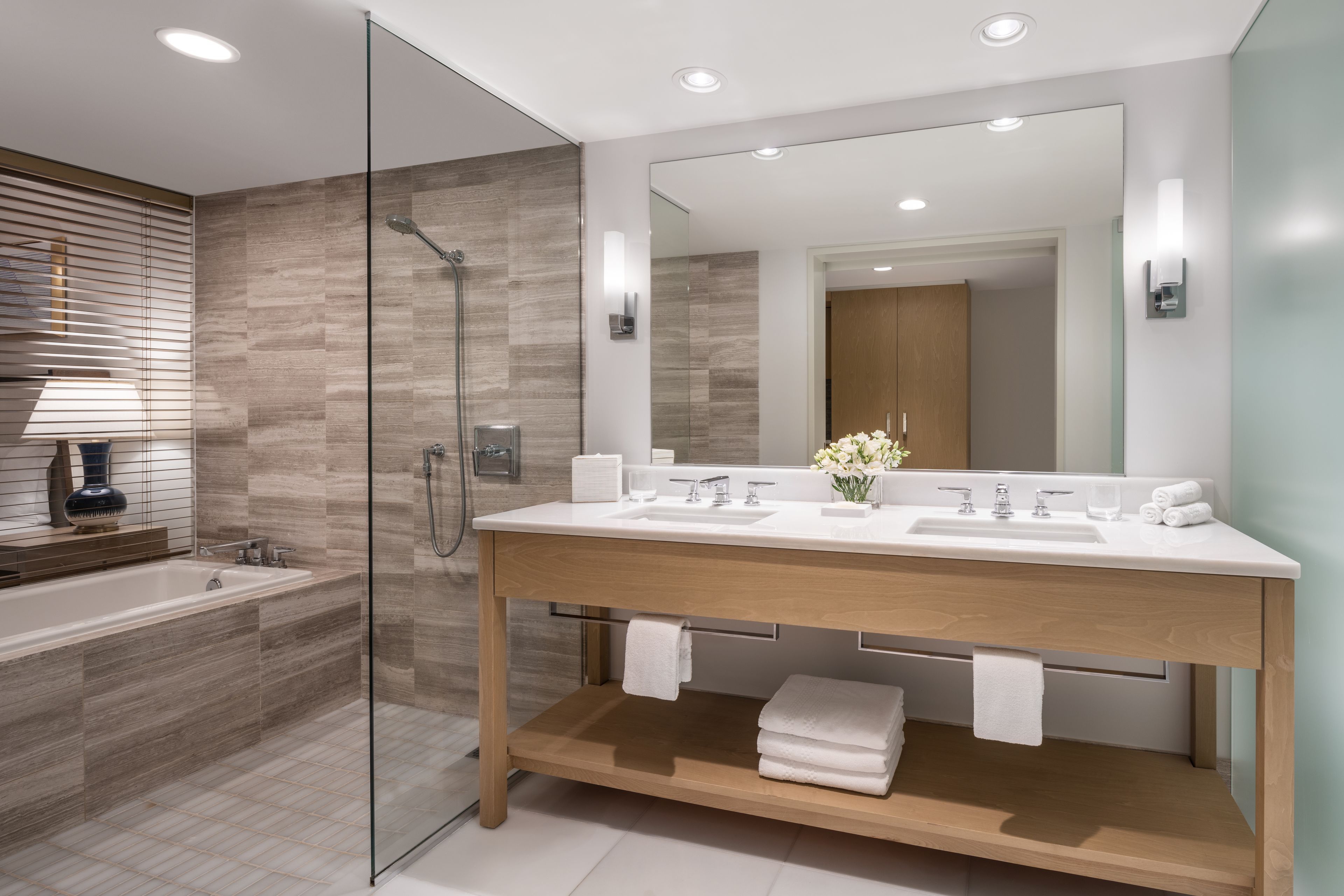A modern bathroom with a glass-enclosed shower, a wooden vanity, and a large mirror.