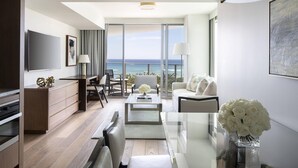 A modern hotel room with a large balcony, a flat-screen TV, a dining area, and a seating space with a view of the ocean. - The Ritz-Carlton Residences, Waikiki Beach (Honolulu)