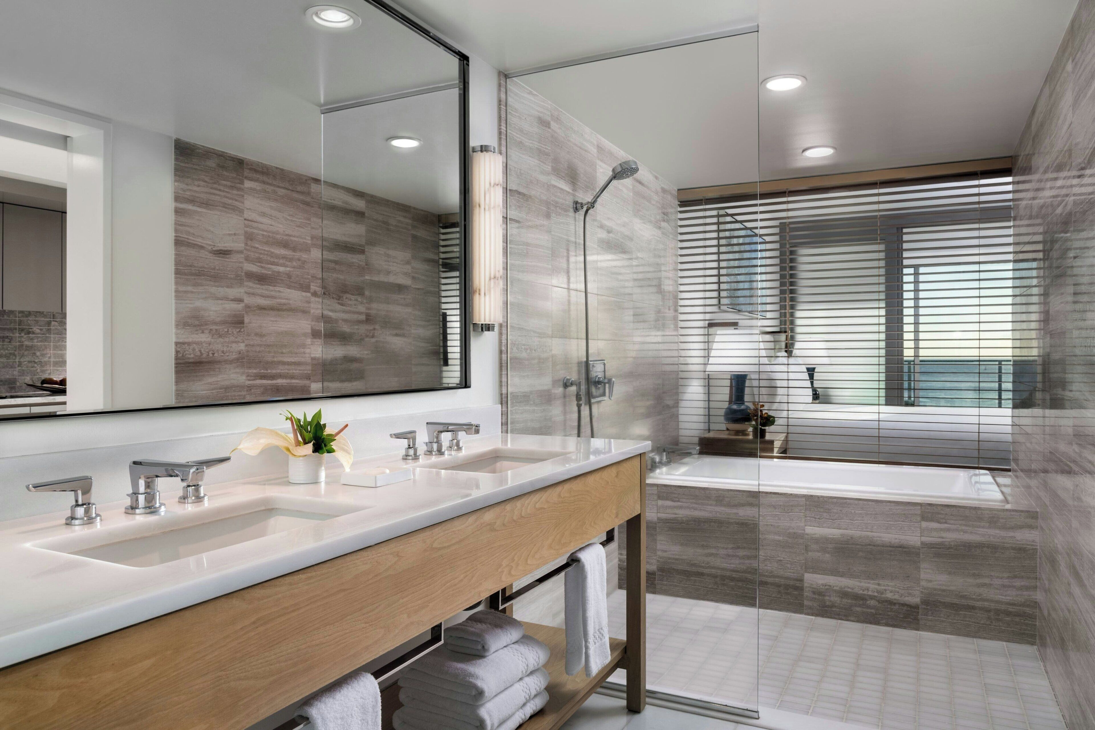 Un baño moderno con un espejo grande, lavamanos dobles, ducha y bañera.