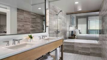 Un baño moderno con un espejo grande, lavamanos dobles, ducha y bañera.