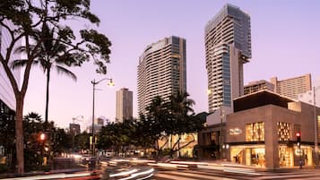 Une vue urbaine avec des immeubles modernes de grande hauteur, un passage piéton et une rue où circulent des véhicules.