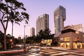 A cityscape with modern high-rise buildings, a crosswalk, and a street with moving vehicles.