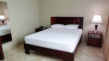 A neatly made bed with white linens, a wooden headboard, and two bedside tables with lamps.