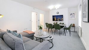 Una sala de estar moderna con un sofá gris, una mesa de centro y un comedor con una mesa y sillas.