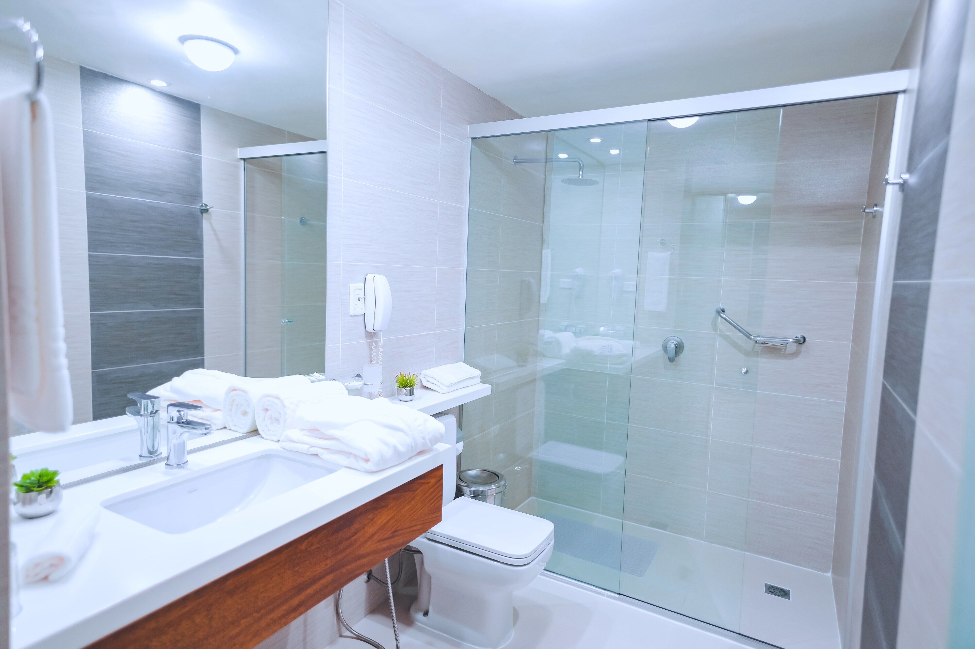Un bagno moderno con doccia vetrata, lavandino bianco e specchio.
