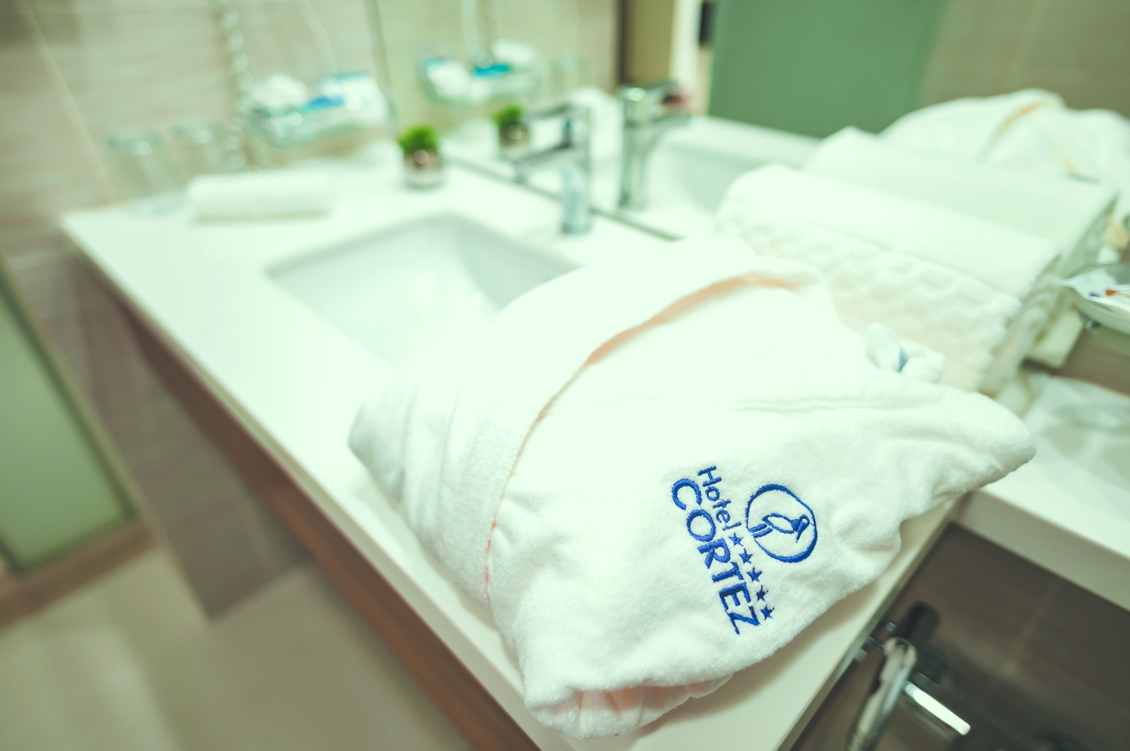 A bathroom with a white sink, a towel, and toiletries.