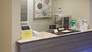 Un comptoir d’accueil avec un téléphone, une caisse enregistreuse et divers panneaux d’information.