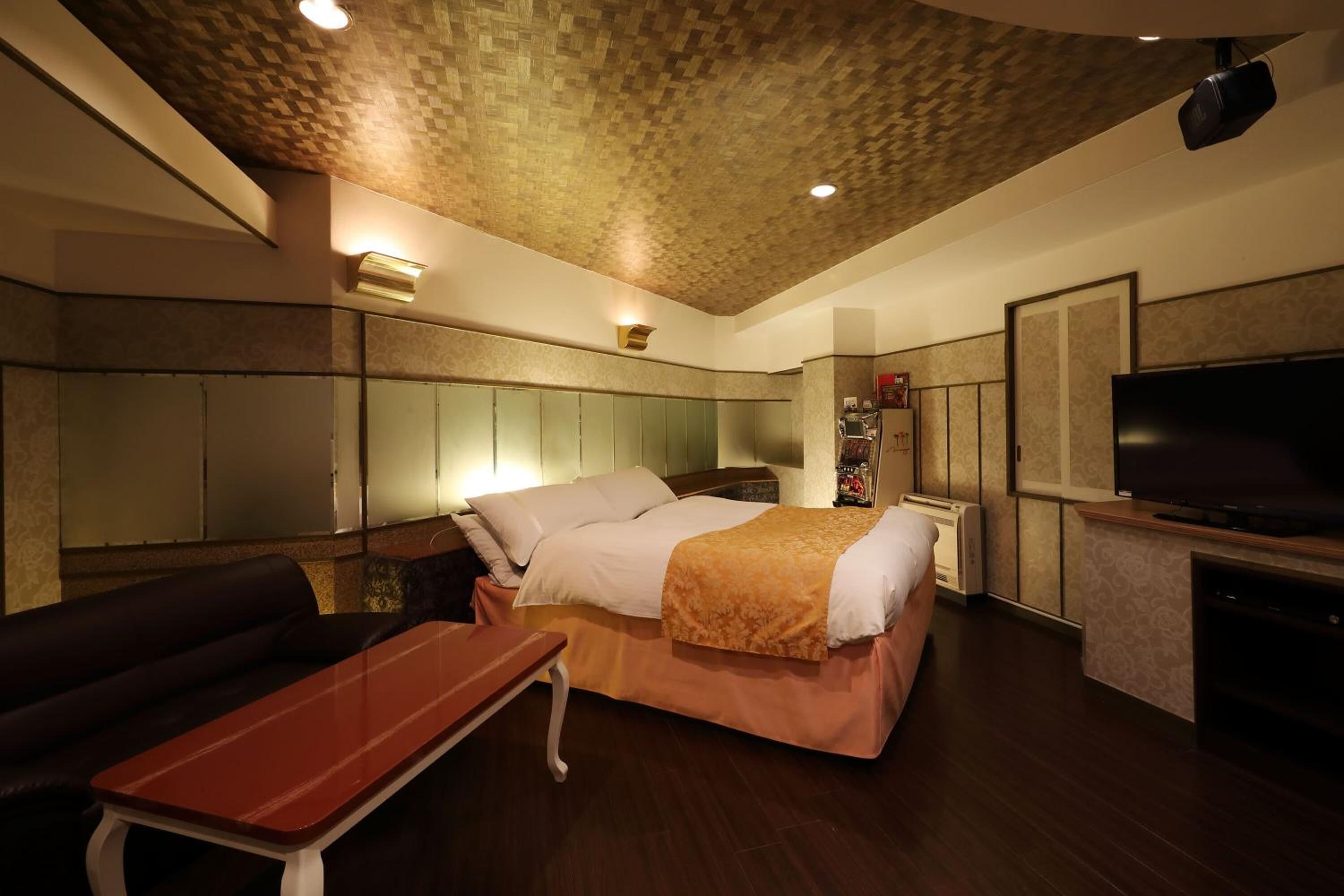 A hotel room with a bed, a sofa, a TV, and a small table.
