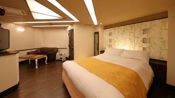 Habitación de hotel con cama, escritorio, silla, televisor y pared con estampado floral.