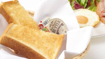 A basket containing a slice of toasted bread, a container of soft whipped butter, a plate with a fried egg, and a side salad.