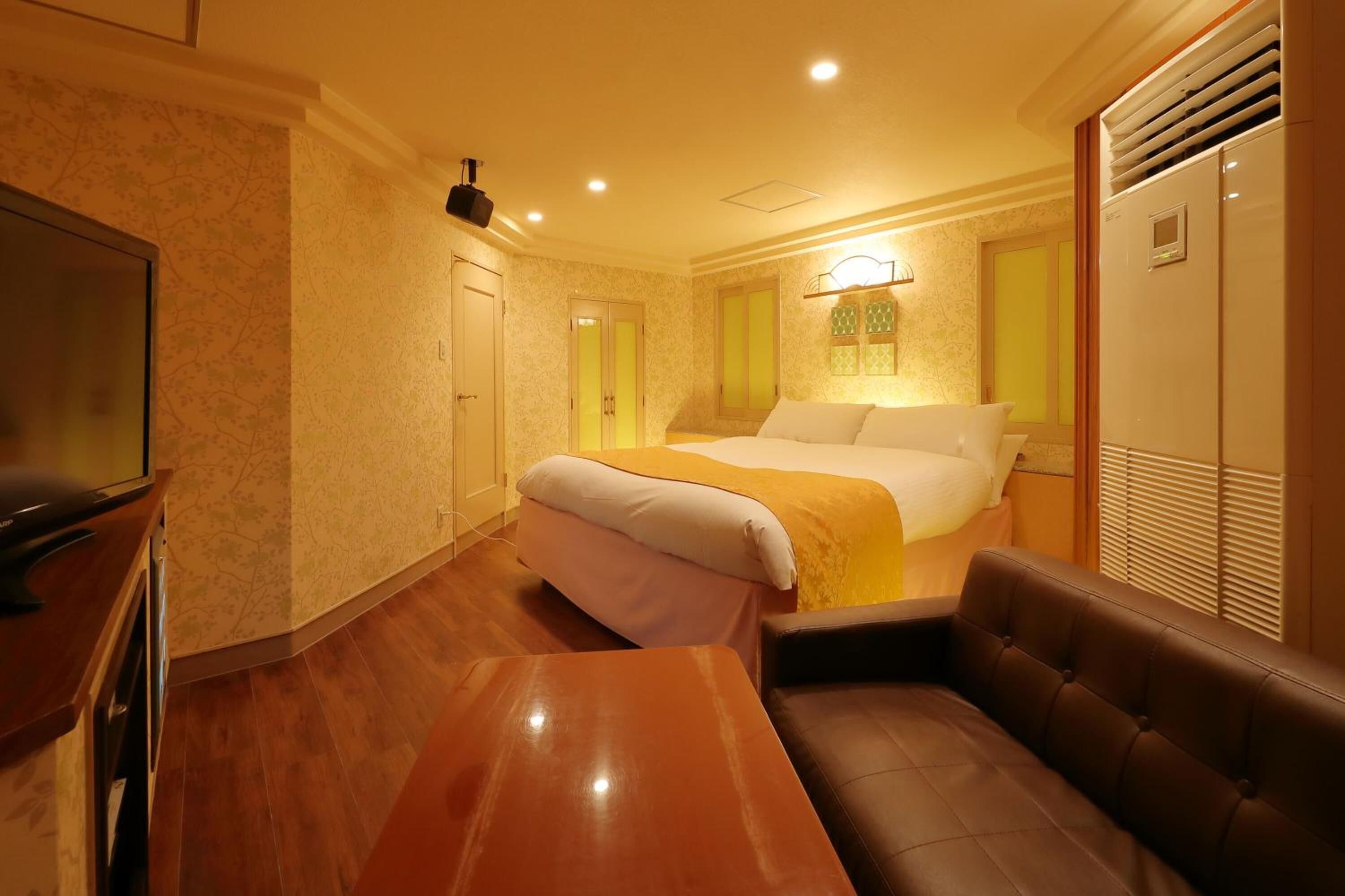 Habitación de hotel con cama, sofá, televisión y escritorio.