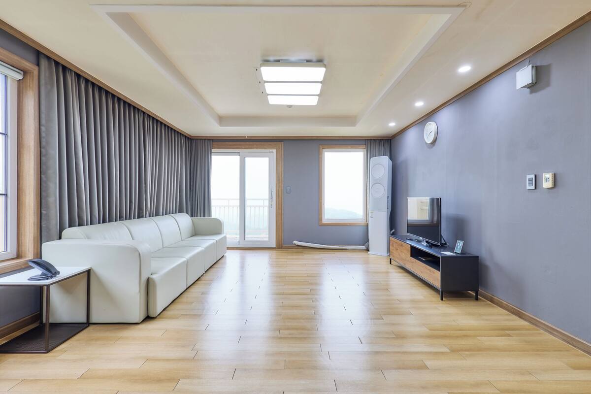 A modern living room with a sofa, a TV, and a wooden floor.