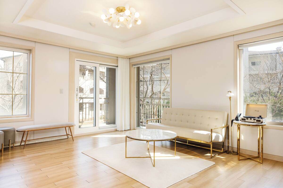 A spacious living room with a white sofa, a round coffee table, and a bench.