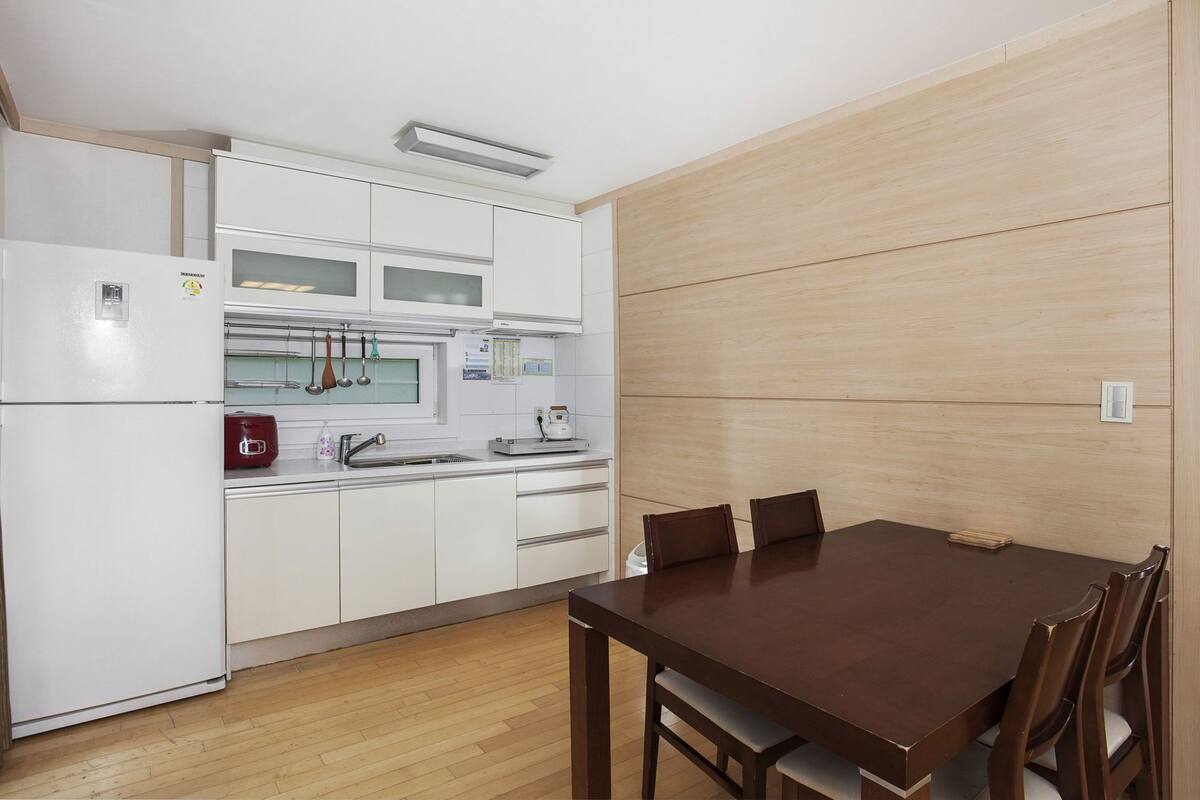 A compact kitchen with white cabinets, a wooden dining table, and a built-in oven.