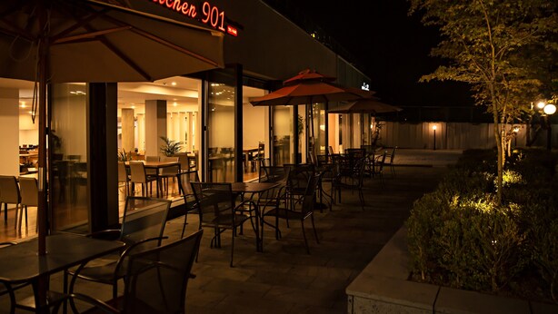 An outdoor dining area with tables and chairs, a neon sign for 'Kitchen 901', and a well-lit entrance to the restaurant. - Palgong Emillia Hotel (Daegu)