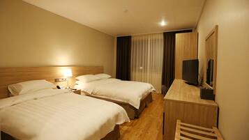 A hotel room with two beds, a desk, a chair, a TV, and a window with curtains.