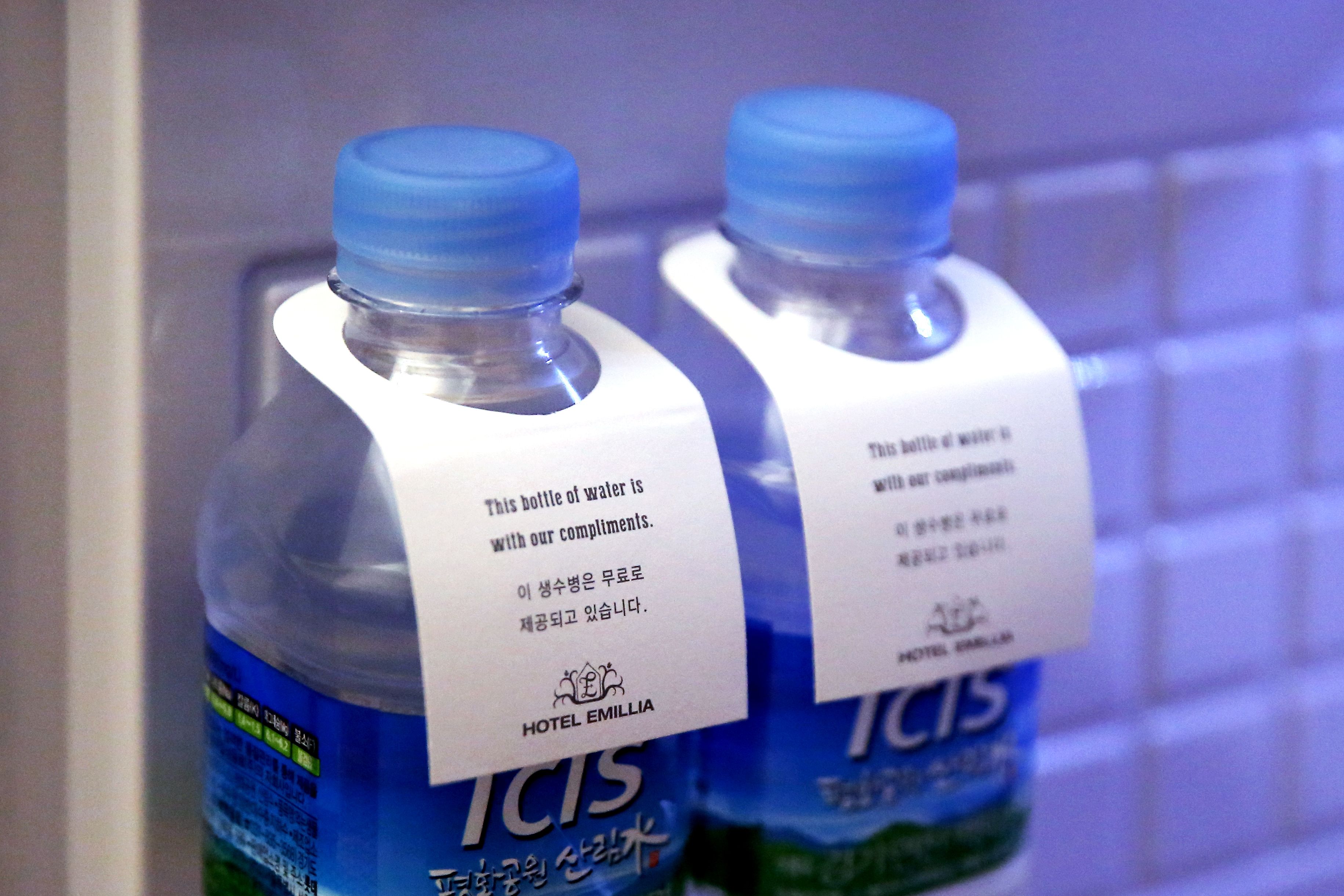 Two bottles of water with labels from Hotel Emillia.