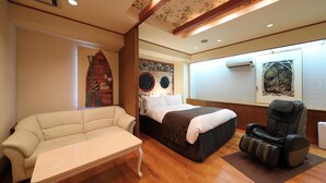 Une chambre à coucher comprenant un lit, un fauteuil de massage, un canapé et une petite table.